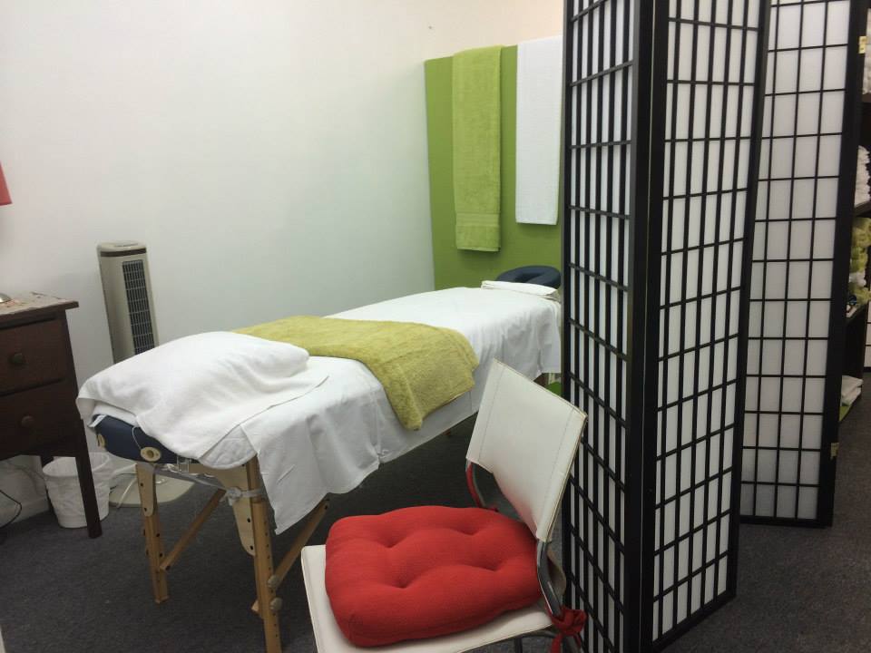 Treatment room with a massage table made up with towels beside a timber privacy screen