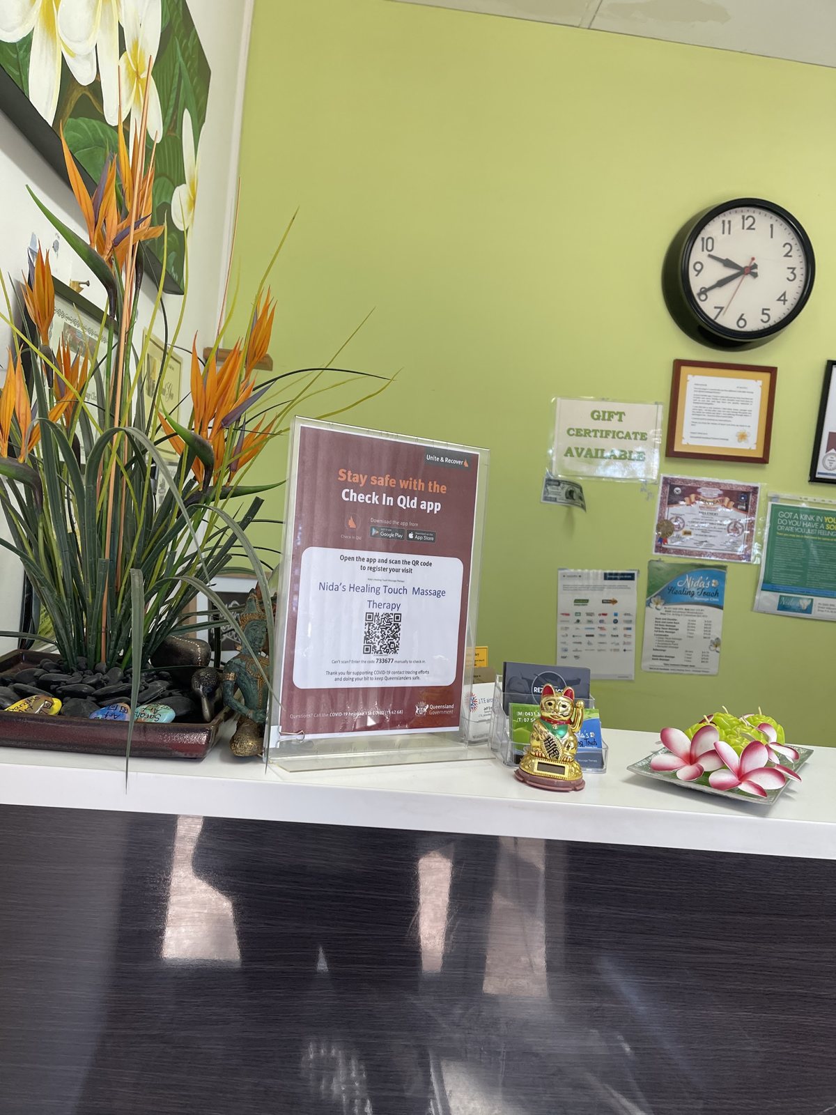 The reception counter with a bird of paradise arrangement, frangipani flowers and a gift certificates sign