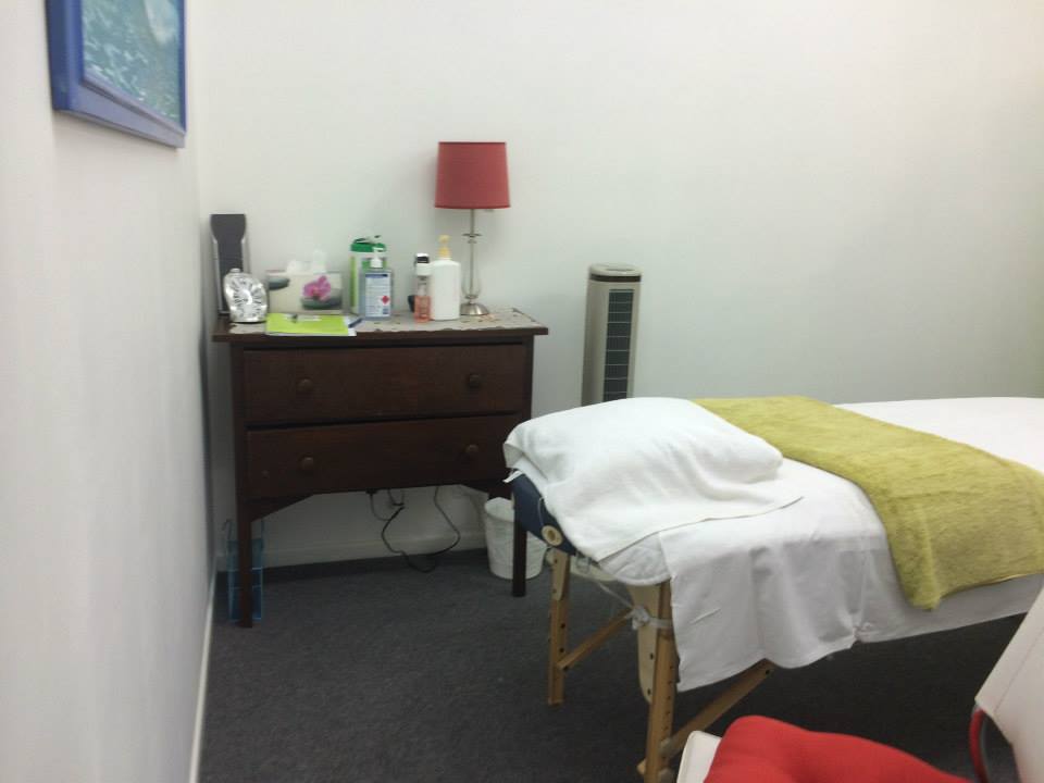 Treatment room with a timber dresser, lamp and made-up massage table